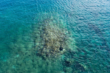 The turquoise sea background, through water the seabed stones is visible