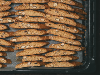 Italian Biscotti cookies dry on the baking sheet.  The cookies are lined in rows.