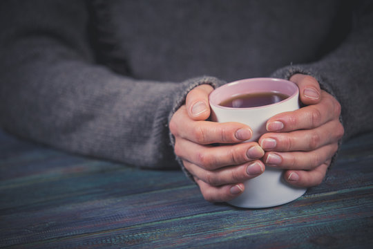Woman holds a cup of hot tea. Cozy morning at home.