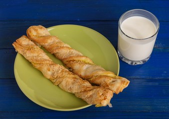 Puff pastry on a plate and a glass of milk on the table.