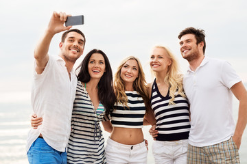 friendship, summer holidays and people concept - group of happy friends taking picture by...