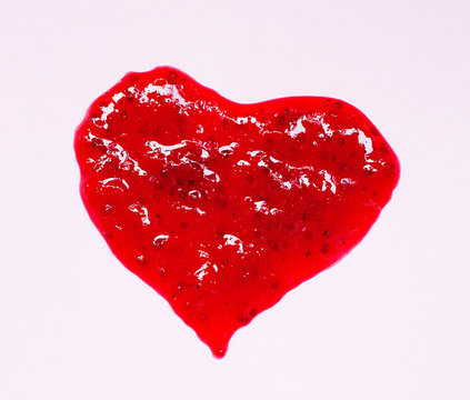 Spot of red berry jam. Shape of heart on pink background