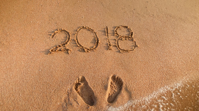 Closeup image of 2018 new year written on wet beach sand. Perfect image to illustrate Christmas, winter holidays, travel and tourism.