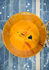 A vibrant large pot of yellow acrylic block printing and screen printing paint, in a bucket in an industrial creative art studio setting.