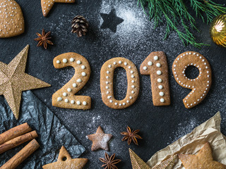 Ginger biscuits of the form of numbers and 2019 new year ginger cookies on dark background. Top view. Seasonal packaging and New Year's attributes