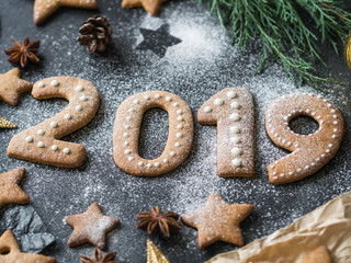 Ginger biscuits of the form of numbers and 2019 new year ginger cookies on dark background. Top view. Seasonal packaging and New Year's attributes