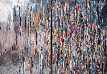 Artistic colourful ink and paint drips on a silver metallic textured background in an industrial artists studio. perfect for artistic backgrounds.