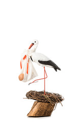 decorative stork holding baby nappy with doll and standing in wicker nest isolated on white © LIGHTFIELD STUDIOS