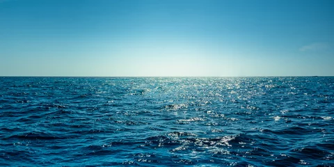 Poster Blauw oceaanpanorama met zonreflectie, de uitgestrekte open zee met heldere lucht, rimpelgolf en kalme zee met prachtig zonlicht © peangdao