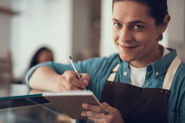 Close up of cheerful waiter smiling and making notes