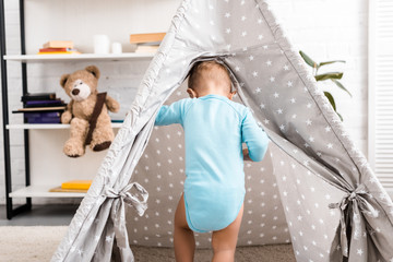 toddler boy in blue bodysuit standing in grey baby wigwam © LIGHTFIELD STUDIOS
