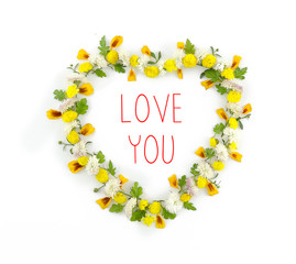 Flowers composition. Heart symbol made of various yellow flowers on white background. Flat lay, top view love you