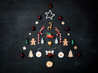 Christmas tree shaped out of different Christmas deco items, on black chalkboard