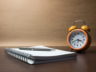 alarm clock and notepad on table