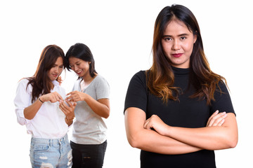 Young Asian woman with arms crossed with two happy friends at th