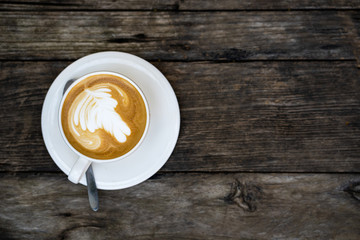 The top view on a cup of coffee on a wooden table