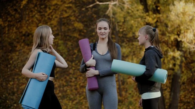Group of Young women preparing for yoga exercises in the autumn city park. Health lifestyle concept.