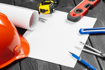 Naklejka premium Close up orange hardhat and variety of repair tools with copy space in the middle over wooden background