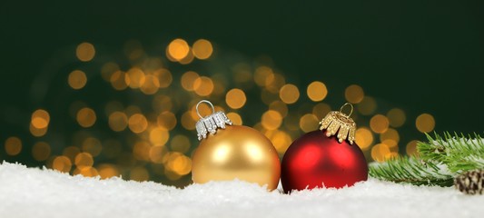 Christmas background - christmas balls and pine branches in the snow with blurred lights in the...