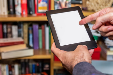 Male hands holding digital reading device in front of bookshelves