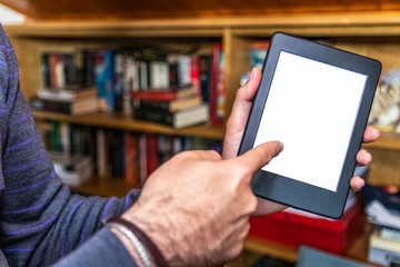 Male hands holding digital reading device in front of bookshelves