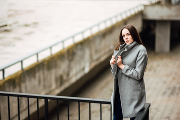 beautiful young girl in a gray coat in an urban environment, lovely woman walking outdoors