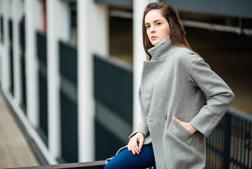 beautiful young girl in a gray coat in an urban environment, lovely woman walking outdoors