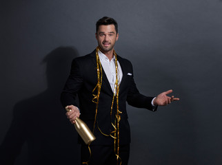 Man holding a bottle of champagne and pointing at copy space