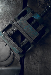 A dirty well used moody and atmospheric blue oily industrial vice in a dark photographic setting, photographed from above. Cinematic lighting. Industry.