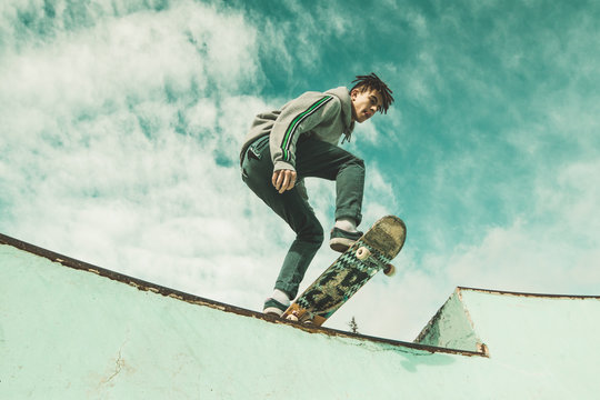Guy skateboarder riding a skateboard on a skatepark. Young man jumping with a skateboard