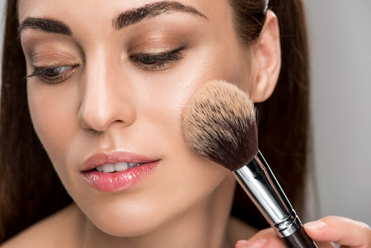 attractive girl applying powder on face with cosmetic brush