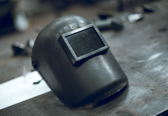 A rustic well worn gritty industrial welders mask in an atmospheric factory setting. Moody...