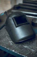 A rustic well worn gritty industrial welders mask in an atmospheric factory setting. Moody atmospheric lighting. Post apocalyptic headwear.