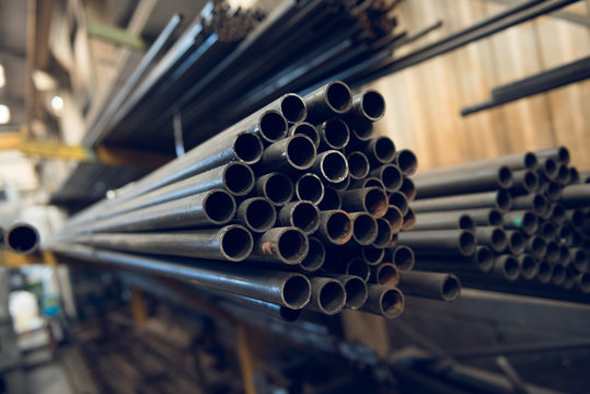 Industrial metal piping in a cold hard industrial factory setting. Metal iron cut pipes being prepared for scaffolding manufacture.