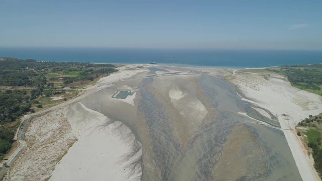 Mountain river Bucao flowing into the sea in Philippines,Luzon. Aerial view river among farmer fields flowing into the blue ocean.