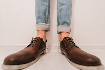 Part of men's legs in rolled up jeans and boots isolated on light background