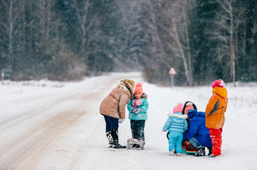big family with sled in snowy woods. Mothers with children on winter walk