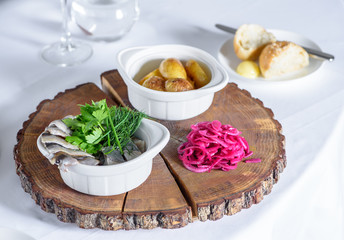 Herring, red onion and potato on wooden plate.