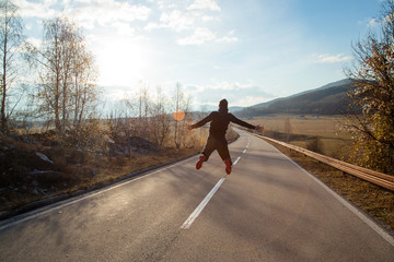 Man celebrating freedom,young man jumping high up in middle of empty road