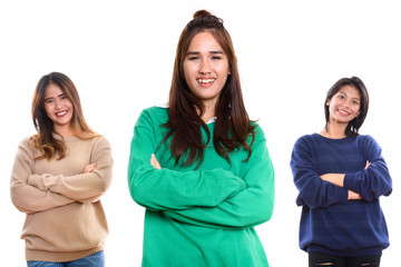 Studio shot of three happy young Asian woman friends smiling wit