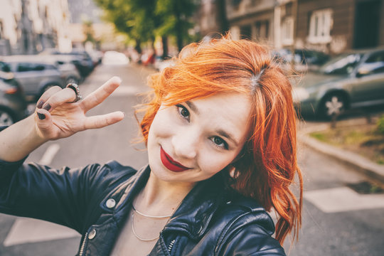 portrait of fashionable young woman wearing a leather jacket taking selfie with smartphone