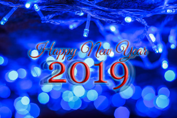 "Happy New Year 2019" red letters inscription on abstract upside down celebratory background with garland lamp and blue light illumination with bokeh effect