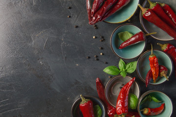 chili peppers with basil and peppercorns in bowls on a rustic surface,