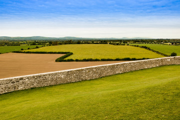 Irish countryside outside Cashel with the pastures broken up by rows of hedges and a beautiful stone wall in front