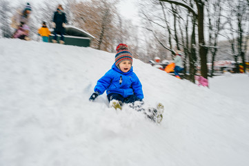 child rolls down from snow mountain. Winter children's fun