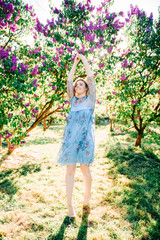 Young girl dancing in blooming garden on summer day