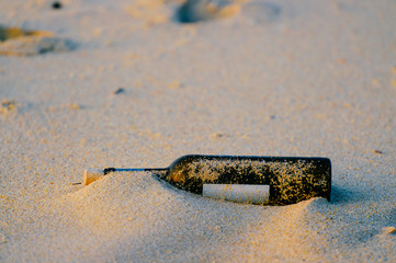 Message in glass bottle in sand on beach outdoors