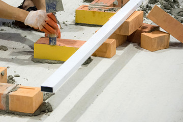 Bricklayer installing bricks, Bricklayer worker installing brick masonry on exterior wall with trowel putty knife.