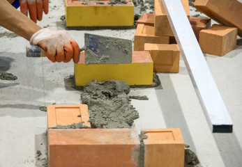 Bricklayer installing bricks, Bricklayer worker installing brick masonry on exterior wall with trowel putty knife.