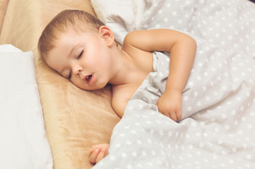 Cute two year old baby boy sleeping in his bed